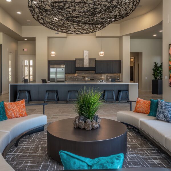 Modern apartment clubhouse lounge with curved seating, artwork, and kitchen.
